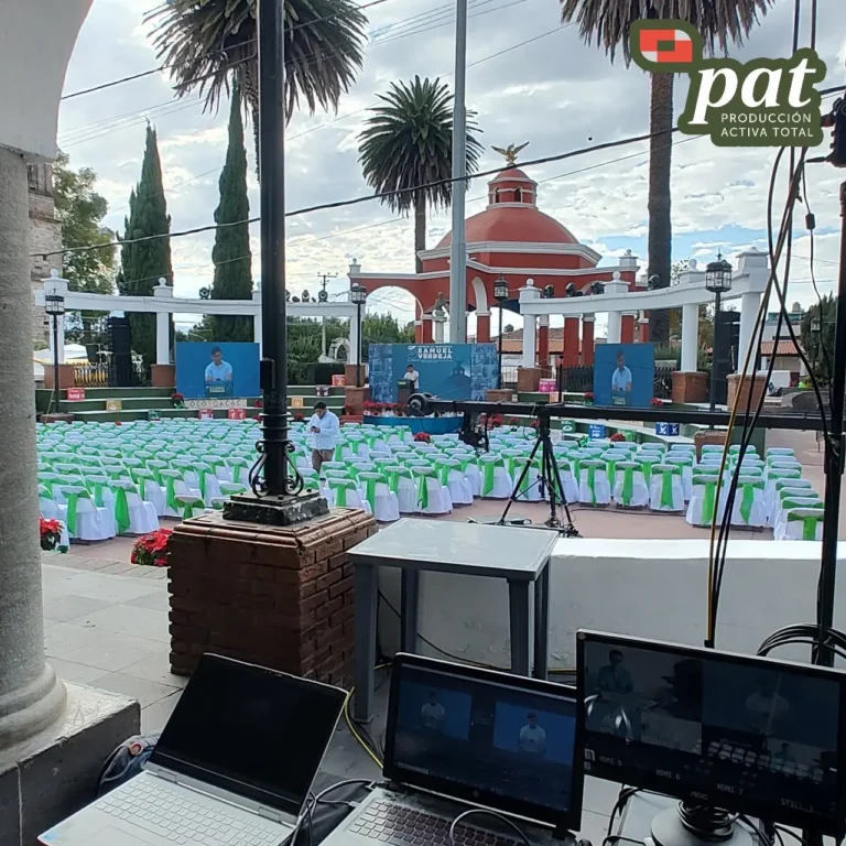 Montaje audiovisual para evento corporativo con monitores, laptops, podium y equipo técnico profesional.
